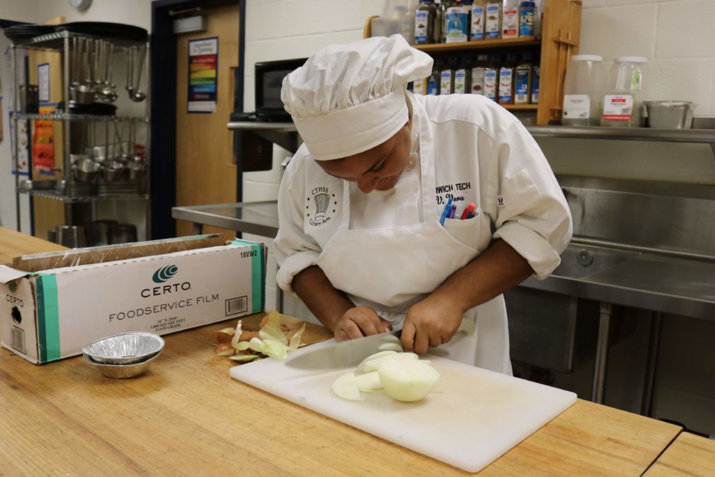 Culinary student chopping onions.