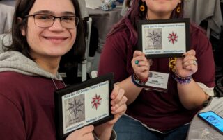 Two Leos posing with their Compass Rose Leo pin contest winning design.